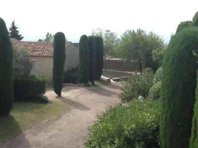 a garden with a row of trees and a house at Gordes Le Bastidon in Gordes