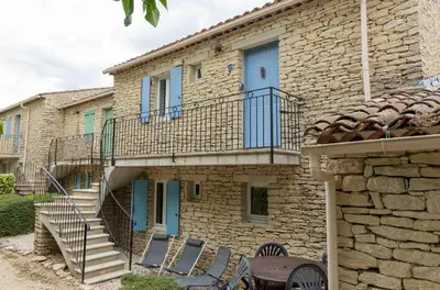 a stone house with a staircase and chairs in front of it at Gordes Le Bastidon in Gordes