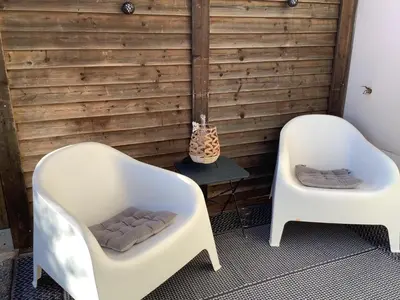 two white chairs in front of a wooden wall at Maison de vacances Aubignan in Aubignan