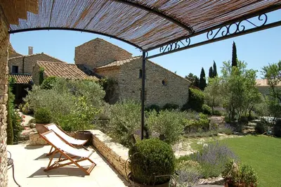 a patio with two chairs sitting under a pergola at Mas de la Beaume in Gordes