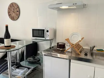 a kitchen with white cabinets and a sink and a microwave at Studio cœur de ville avec salle de bain privative & kitchenette in Carpentras