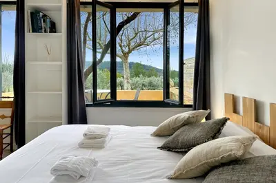 a bedroom with a bed with pillows and a window at Appartement I Bastide La Gravière I Electio in Lourmarin
