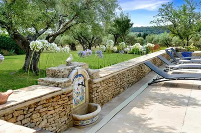 a stone retaining wall with a fountain on a patio at Appartement I Bastide La Gravière I Electio in Lourmarin