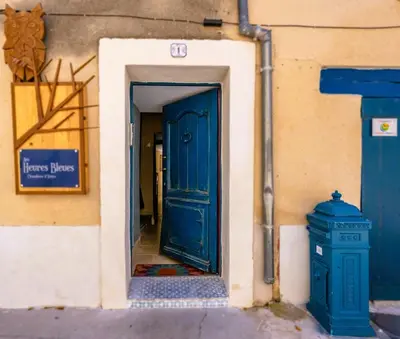 a blue door in a building with a fire hydrant at Aux Heures Bleues in LʼIsle-sur-la-Sorgue