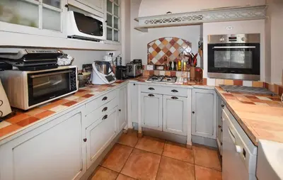 a kitchen with white cabinets and orange tile floors at Nice Home In Entraigues-Sur-La-Sorg in Entraigues-sur-la-Sorgue