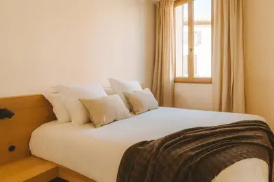 a bedroom with a bed with white sheets and a window at Le Saint Hubert in Saint-Saturnin-les-Apt