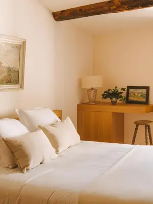 a bedroom with a bed with white sheets and a table at Le Saint Hubert in Saint-Saturnin-les-Apt