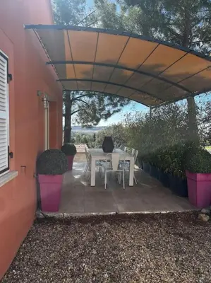 a patio with a table and chairs under an umbrella at La villa Rosa in Bédoin