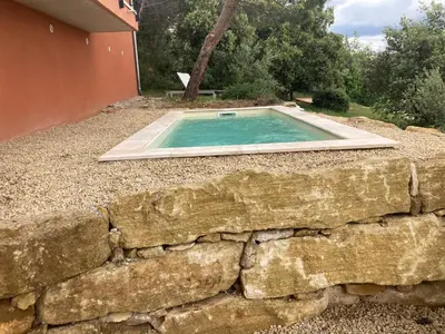 a pool in a stone wall next to a house at La villa Rosa in Bédoin