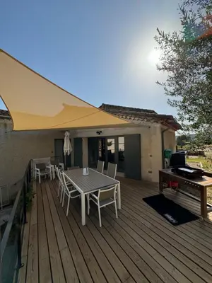 a wooden deck with a table and a yellow umbrella at La Grange de Paulette in Bédoin