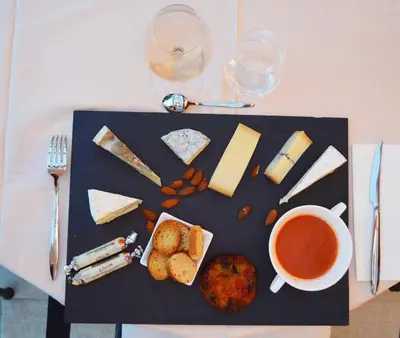 a tray with a variety of cheese and a cup of wine at Le Domaine d'Euphony in Monteux