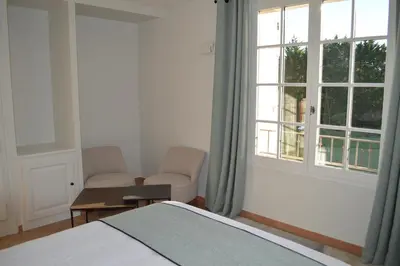 a bedroom with a bed and two chairs and a window at Le Domaine d'Euphony in Monteux