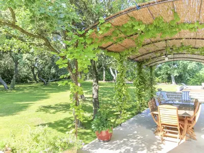 a patio with a table and chairs under a pergola at Le Jardin des Chenes in Eyragues