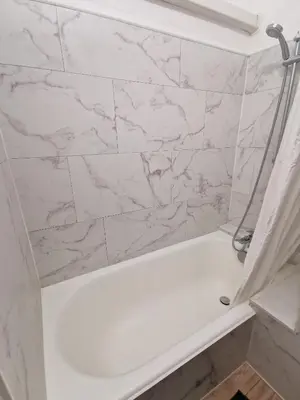 a white bath tub with a marble wall at Appart'Cosy - clim - terrasse - ascenseur in Cavaillon