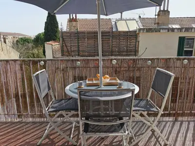 a table and chairs with an umbrella on a deck at Appart'Cosy - clim - terrasse - ascenseur in Cavaillon