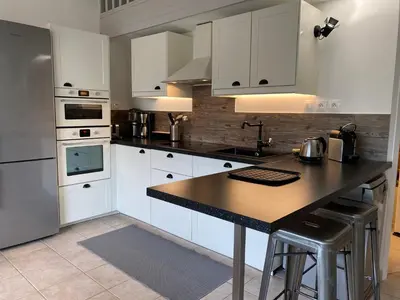 a kitchen with white cabinets and a black counter top at Beau Duplex climatisé T3 vue panoramique Luberon in Pertuis