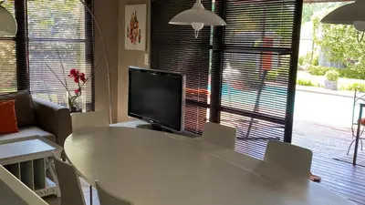 a living room with a white table and a television at Maison AdriAnna in Vedène
