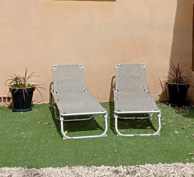 two metal chairs sitting next to a building at Gîte PITCHOU au pied du VENTOUX in Flassan