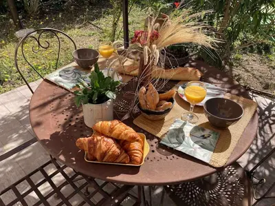 a wooden table with bread and croissants on it at Le charme de Landra in Pernes-les-Fontaines