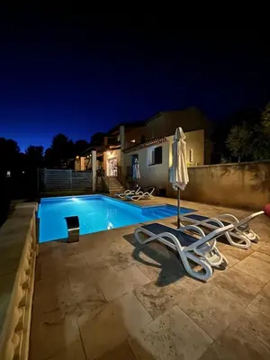 a swimming pool with two lawn chairs and an umbrella at Villa avec vue in Sainte-Tulle