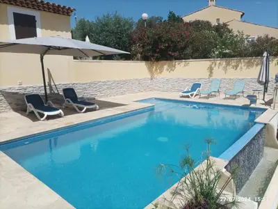 a swimming pool with two chairs and an umbrella at Villa avec vue in Sainte-Tulle