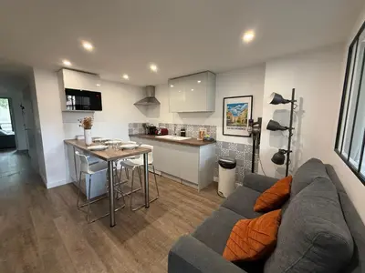 a living room with a couch and a kitchen at L'Amandier - Joli appartement T3 neuf centre ville à 2 pas de la Rotonde Mirabeau et des Allées Provençales in Aix-en-Provence