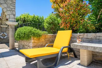 a yellow chair sitting next to a stone wall at La Maison de Sophie in Châteauneuf-de-Gadagne