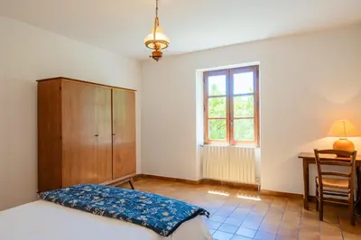 a bedroom with a bed and a desk and a window at La Maison de Sophie in Châteauneuf-de-Gadagne