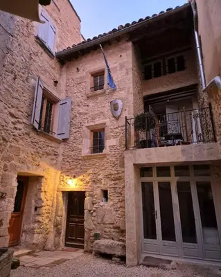 an old stone building with windows and a balcony at Au Lys rose in LʼIsle-sur-la-Sorgue