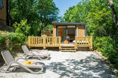 a small cabin with two chairs and a porch at Camping Le Luberon in Apt