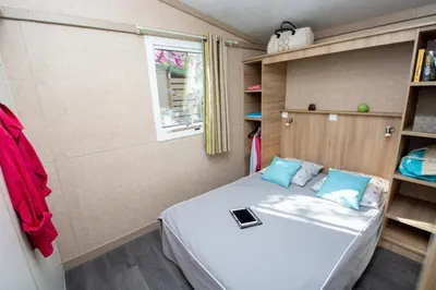 a small bedroom with a bed with a tablet on it at Camping Le Luberon in Apt