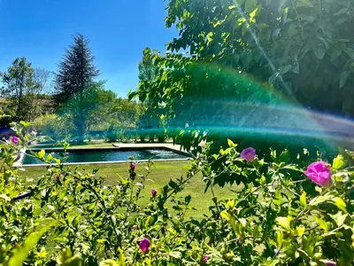 a rainbow over a garden with a pond at Domaine d'Hestia le gite Victoria in Rognes