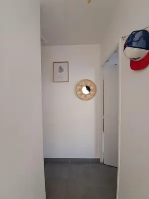 a hallway with white walls and a door with a clock at Appartement cosy centre Robion in Robion en Luberon