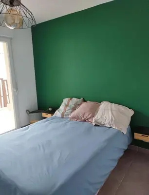 a bedroom with a green wall and a bed with pillows at Appartement cosy centre Robion in Robion en Luberon