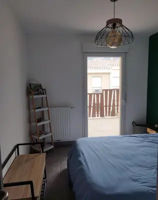 a bedroom with a bed and a table and a window at Appartement cosy centre Robion in Robion en Luberon