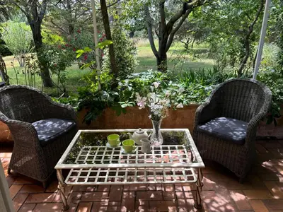 a patio with three chairs and a table with cups and flowers at The Olive Garden - Charming Villa for 10 with pool and fast Wifi in Caromb