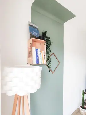 a shelf with books and a lamp on a wall at Le Cosy Valcros, design et confort in Aix-en-Provence