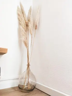 a glass vase with feathers in it on a table at Le Cosy Valcros, design et confort in Aix-en-Provence