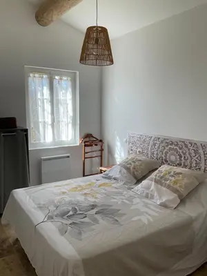 a bedroom with a bed with a white comforter at La jasse in Cabrières-dʼAigues