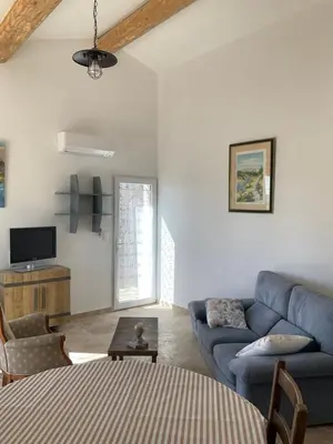 a living room with a blue couch and a tv at La jasse in Cabrières-dʼAigues