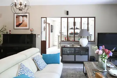 a living room with a white couch and a tv at Profitez de la quiétude en bord de rivière, à 5 min du centre ville in LʼIsle-sur-la-Sorgue