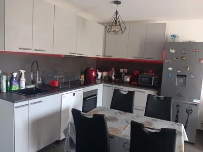 a kitchen with white cabinets and a table with chairs at MIRANEO in Miramas