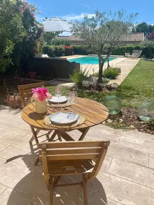 a wooden table and bench with a table and flowers on it at Au pied du luberon in Pertuis