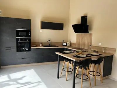 a kitchen with black cabinets and a island with bar stools at Le capèu in Mollégès