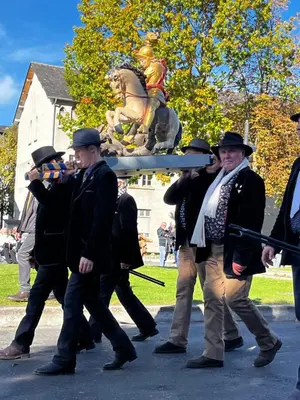 a group of men walking down a street with a statue at Le capèu in Mollégès