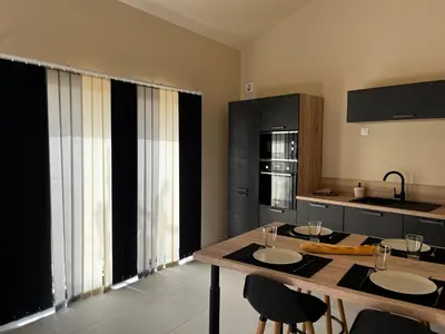 a kitchen with a wooden table with chairs and a counter at Le capèu in Mollégès
