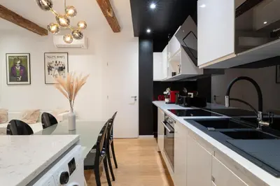 a kitchen with black and white appliances and a table at Le Yona Mirabeau - Appartement T3 Atypique situé dans le centre ville historique - proche Rotonde in Aix-en-Provence