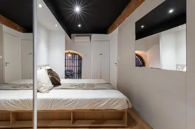 a bedroom with white walls and a bed with a mirror at Le Yona Mirabeau - Appartement T3 Atypique situé dans le centre ville historique - proche Rotonde in Aix-en-Provence