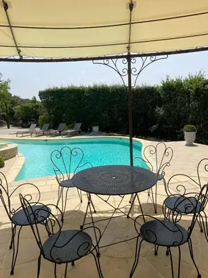 a table and chairs under an umbrella next to a pool at La Souvenance - Listed villa in the hills in Lagnes