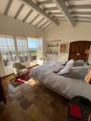 a bedroom with a bed and a chair and windows at La Souvenance - Listed villa in the hills in Lagnes